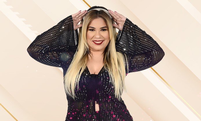 Cantora Marília Mendonça na foto, com roupa preta e segurando uma tiara na cabeça