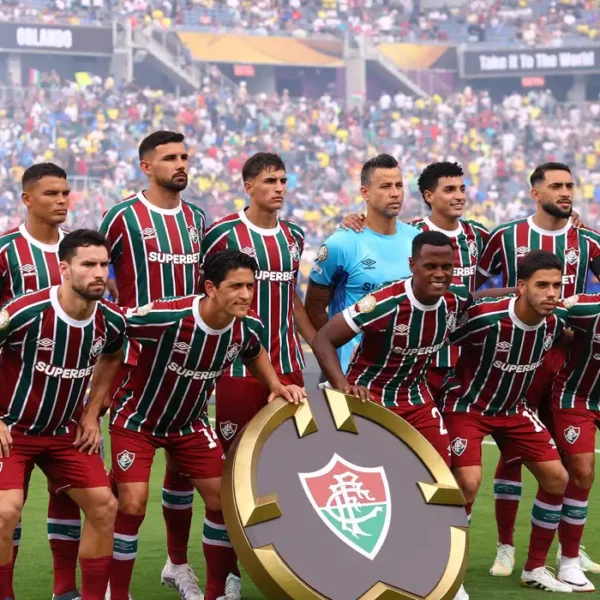 Jogadores do Fluminense posam para foto em campo, segurando o escudo do time, no Mundial de Clubes da FIFA 2025.