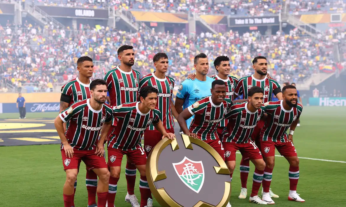 Jogadores do Fluminense posam para foto em campo, segurando o escudo do time, no Mundial de Clubes da FIFA 2025.