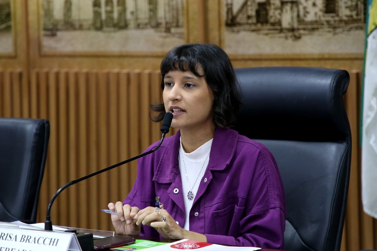Vereadora Brisa Bacchi em sessão no plenário, vestindo jaqueta roxa.
