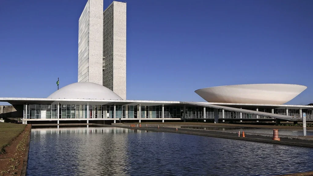 Congresso Nacional refletido no espelho d’água em Brasília, símbolo do poder legislativo que retoma atividades com foco no IR e apostas online