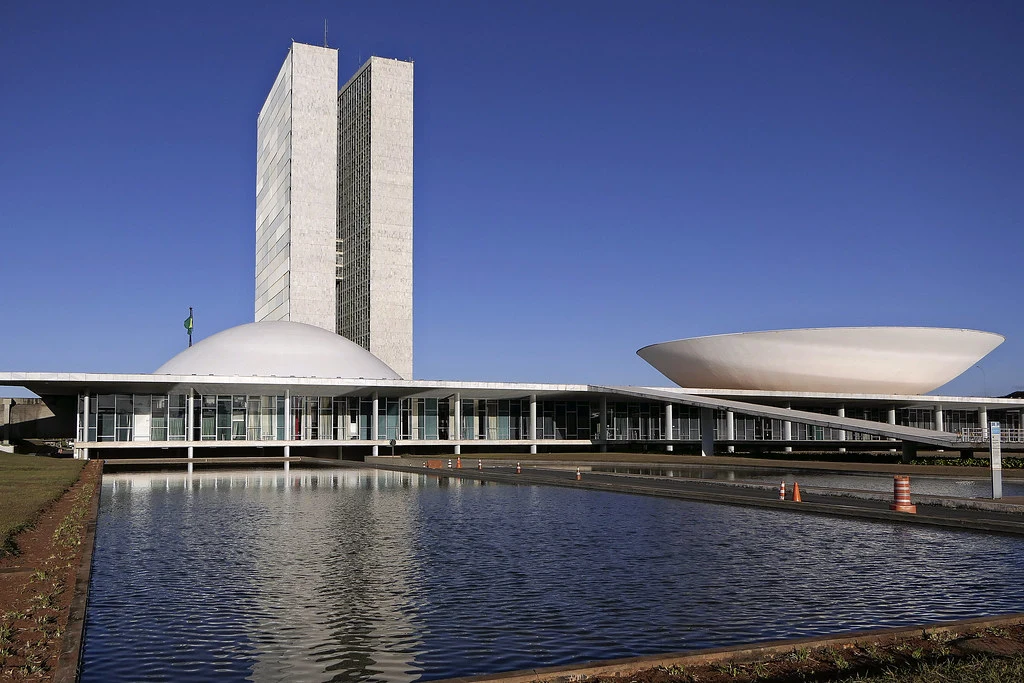 Congresso Nacional refletido no espelho d’água em Brasília, símbolo do poder legislativo que retoma atividades com foco no IR e apostas online