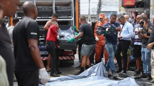 Pessoas colocando os corpos das pessoas mortas na megaoperação, no carro do IML.