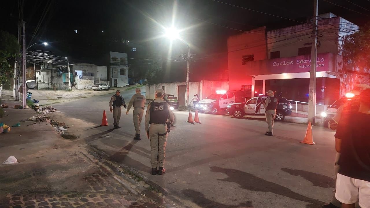 Policiais param carro para verificar documentos na rua de acesso ao bairro de Mãe Luiza.