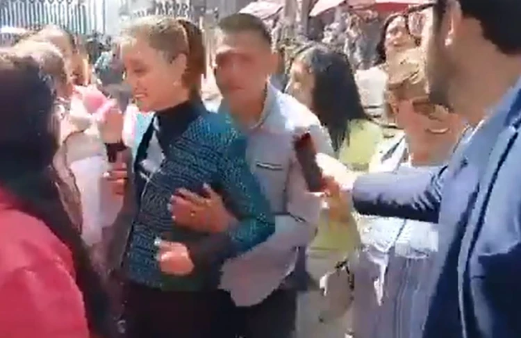 Foto da presidente Claudia Sheinbaum em evento público, cercada por apoiadores sendo assediada por um homem.