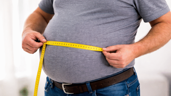 Homem com barriga de chope mede circunferência abdominal com fita métrica, indicando risco para a saúde do coração