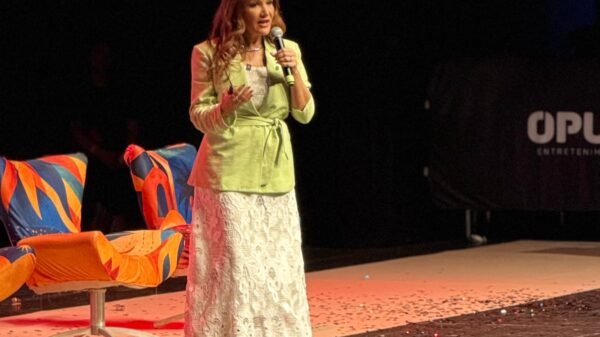 Pri de Sousa, no palco do Teatro Riachuelo, vestindo saia longa branca e Blazer verde, falando sobre Autoridade no marketing digital