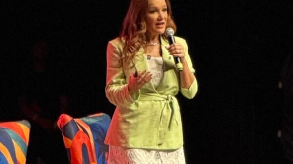 Pri de Sousa, no palco do Teatro Riachuelo, vestindo saia longa branca e Blazer verde, falando sobre Autoridade no marketing digital